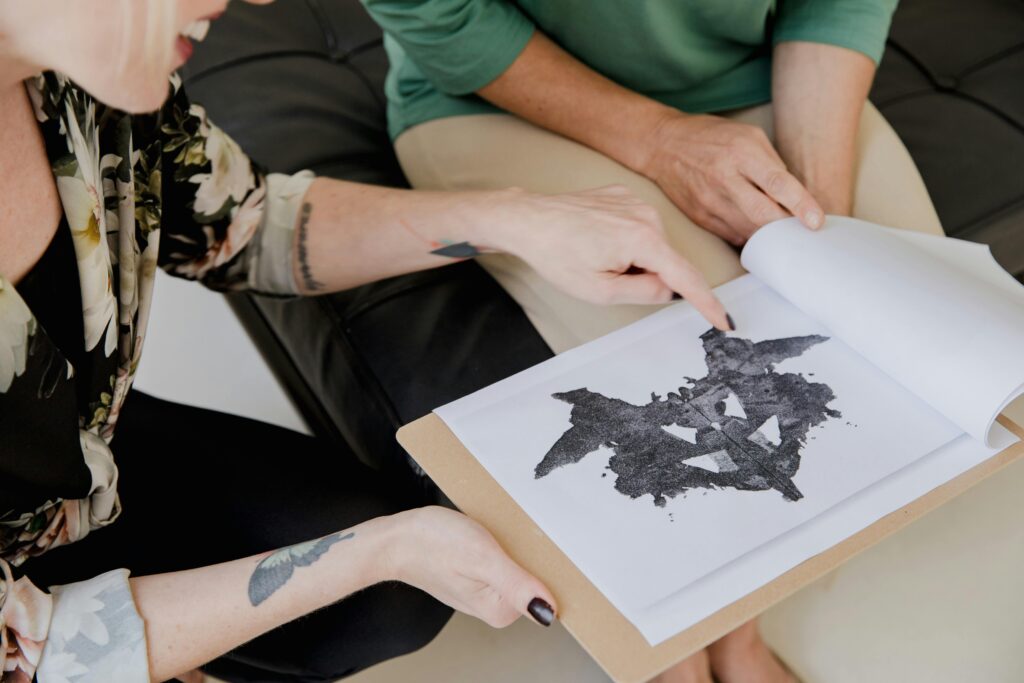 Two adults discuss a Rorschach inkblot test, focusing on interpretation and analysis.